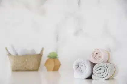 Bamboo wall holders with neatly rolled towels beside a mirror in a bright bathroom