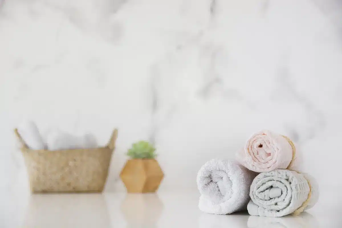 Bamboo wall holders with neatly rolled towels beside a mirror in a bright bathroom