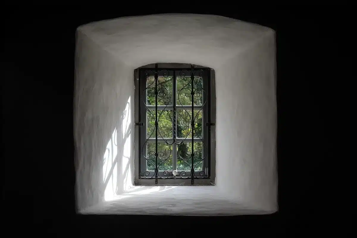 Hands applying adhesive strips to a clean window frame before mounting a pleated shade
